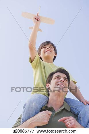 Father carrying son (10-11 years) on shoulders with model airplane View Large Photo Image Stock Photo - Father carrying son (10-11 years) on shoulders with model airplane. Fotosearch