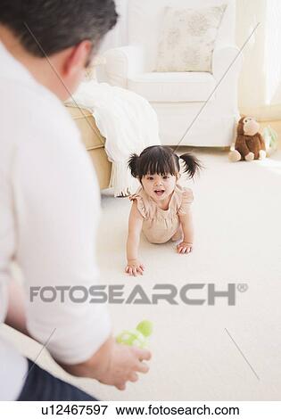 Stock Photo - Father encouraging baby daughter (12-17 months) to crawl. Fotosearch