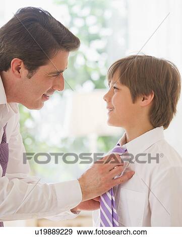 Stock Photo - Father helping son (10-11 years) to tie tie. Fotosearch