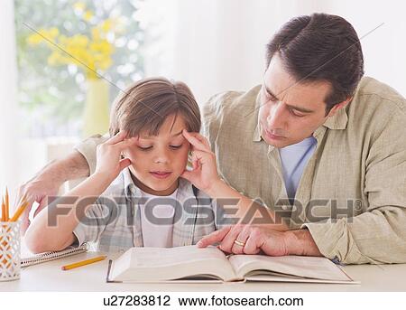 Stock Image - Father helping son (10-11 years) with his homework. Fotosearch