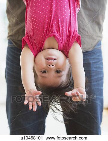 Father holding baby daughter (12-17 months) upside down View Large Photo Image Stock Image - Father holding baby daughter (12-17 months) upside down. Fotosearch