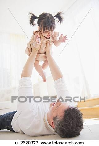 Father lifting baby daughter (12-17 months) while lying on carpet View Large Photo Image Stock Image - Father lifting baby daughter (12-17 months) while lying on carpet. Fotosearch