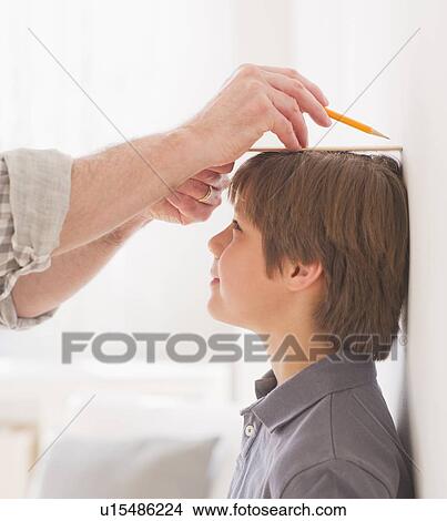 Father measuring son's (10-11 years) height View Large Photo Image Picture - Father measuring son's (10-11 years) height. Fotosearch