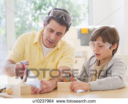 Picture - Father sewing wood with son (10-11 years). Fotosearch
