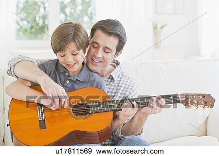 Father teaching son (10-11 years) how to play acoustic guitar View Large Photo Image Stock Photo - Father teaching son (10-11 years) how to play acoustic guitar. Fotosearch