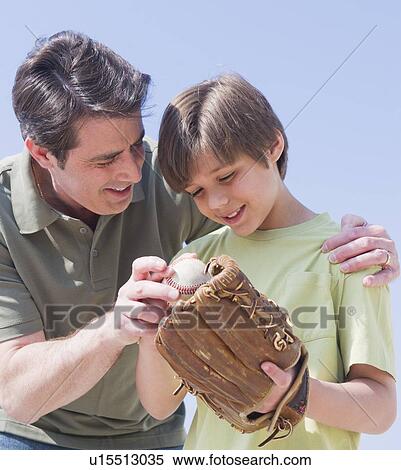 Stock Photography - Father teaching son (10-11 years) how to play baseball. Fotosearch
