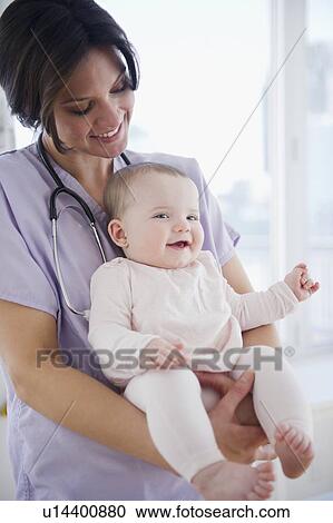 Stock Image - Female nurse with baby girl (6-11 months). Fotosearch