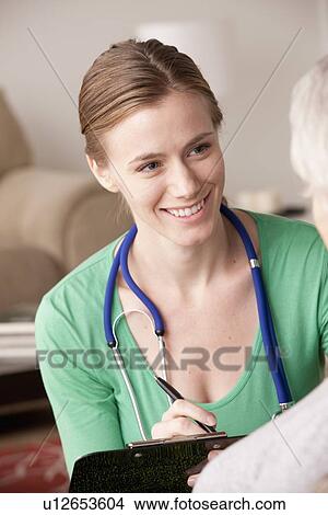 Picture - Female nurse with senior patient at home. Fotosearch