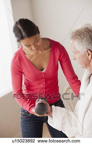 Stock Image - Female nurse with senior patient at home. Fotosearch