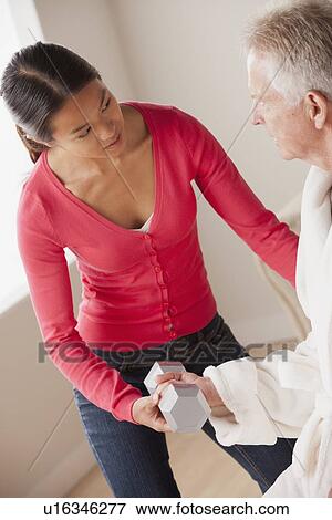 Stock Photo - Female nurse with senior patient at home. Fotosearch