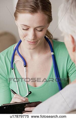 Stock Photography - Female nurse with senior patient at home. Fotosearch