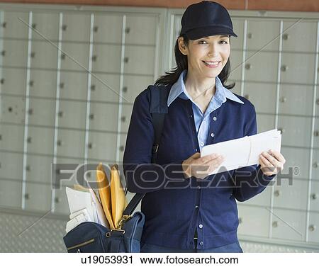 Stock Image - Female postal worker holding letter. Fotosearch