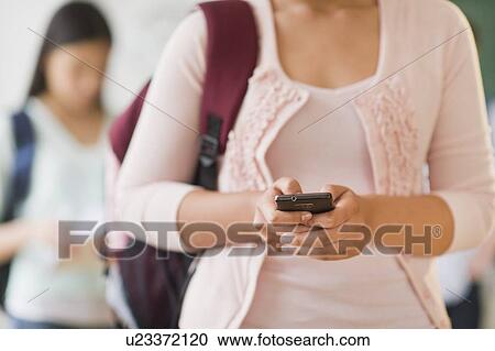 Stock Image - Female student texting on phone. Fotosearch