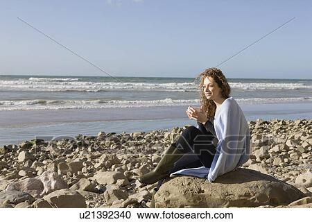 France, Pas-de-Calais, Escalles, Woman wrapped in blanket sitting on rocky beach View Large Photo Image Stock Image - France, Pas-de-Calais, Escalles, Woman wrapped in blanket sitting on rocky beach. Fotosearch