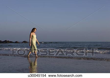 Picture - France, Pas-de-Calais, Escalles, Young woman strolling on empty beach. Fotosearch
