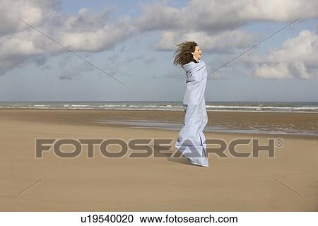 Stock Image - France, Pas-de-Calais, Escalles, Young woman strolling on empty beach. Fotosearch