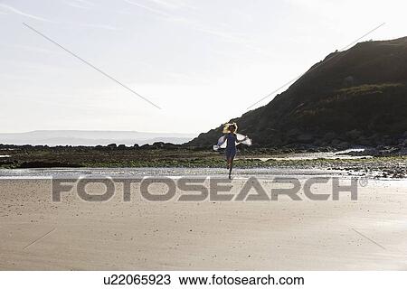 Stock Image - France, Pas-de-Calais, Escalles, Young woman strolling on empty beach. Fotosearch