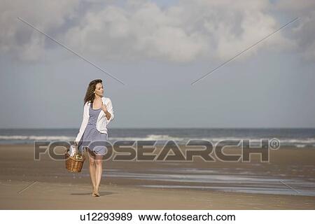 Stock Photo - France, Pas-de-Calais, Escalles, Young woman strolling on empty beach. Fotosearch