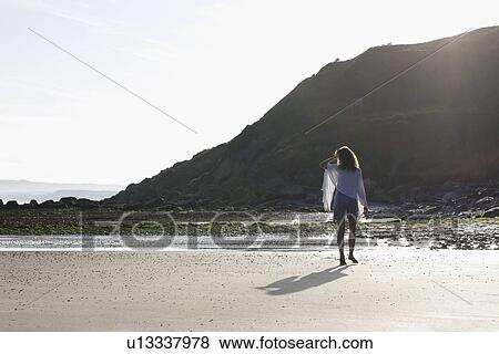 Stock Photo - France, Pas-de-Calais, Escalles, Young woman strolling on empty beach. Fotosearch