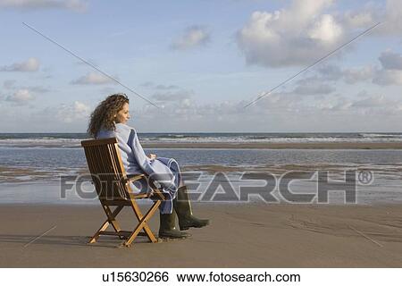 France, Pas-de-Calais, Escalles, Young woman sitting on chair on empty beach View Large Photo Image Stock Photograph - France, Pas-de-Calais, Escalles, Young woman sitting on chair on empty beach. Fotosearch