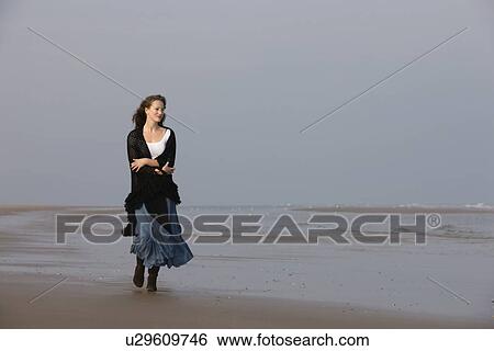 Stock Photograph - France, Pas-de-Calais, Escalles, Young woman strolling on empty beach. Fotosearch