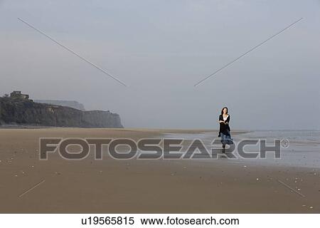 Stock Photography - France, Pas-de-Calais, Escalles, Young woman strolling on empty beach. Fotosearch