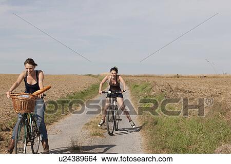 France, Picardie, Albert, Young women cycling on country road View Large Photo Image Picture - France, Picardie, Albert, Young women cycling on country road. Fotosearch