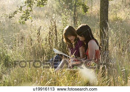 Stock Image - France, Picardie, Albert, Young women relaxing on meadow. Fotosearch