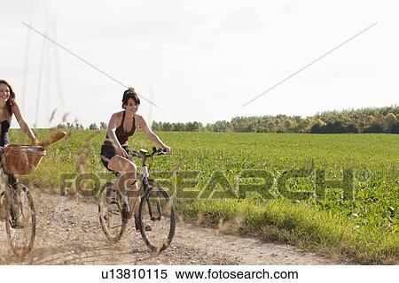 France, Picardie, Albert, Young women on bikes on country road View Large Photo Image Stock Photography - France, Picardie, Albert, Young women on bikes on country road. Fotosearch