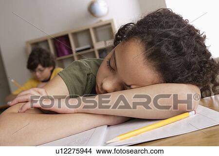 Picture - Girl (10-11) napping on desk with boy (10-11) in background. Fotosearch