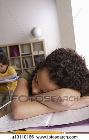 Stock Photograph - Girl (10-11) napping on desk with boy (10-11) in background. Fotosearch