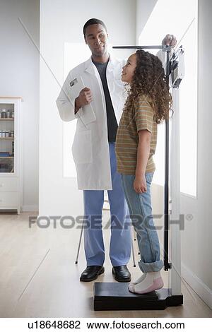 Stock Image - Girl (8-9) at doctor's office. Fotosearch
