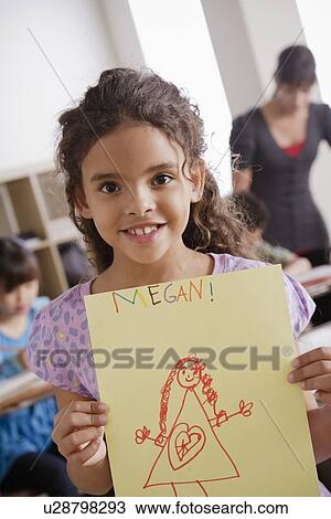 Stock Image - Girl (8-9) showing his drawing. Fotosearch