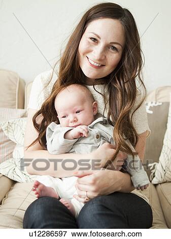Stock Photo - Happy young mother holding baby boy (2-5 months). Fotosearch