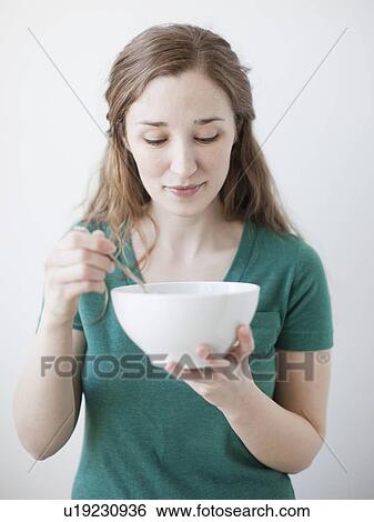 Stock Photograph - Happy young woman enjoying bowl of cornflakes. Fotosearch
