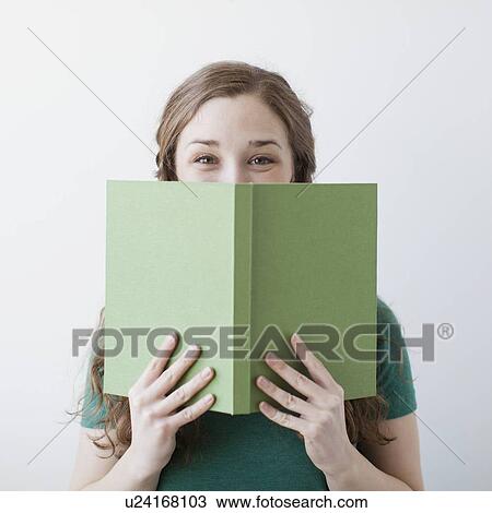 Stock Image - Happy young woman holding green book. Fotosearch