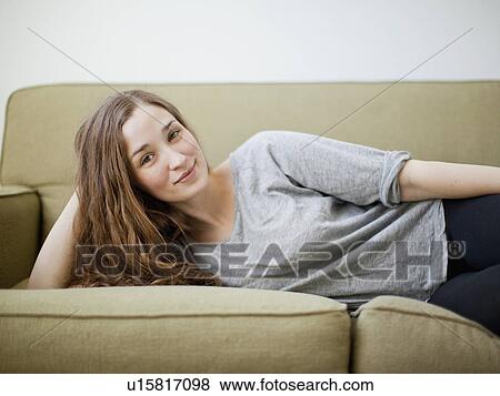 Stock Photo - Happy young woman reclining on sofa. Fotosearch