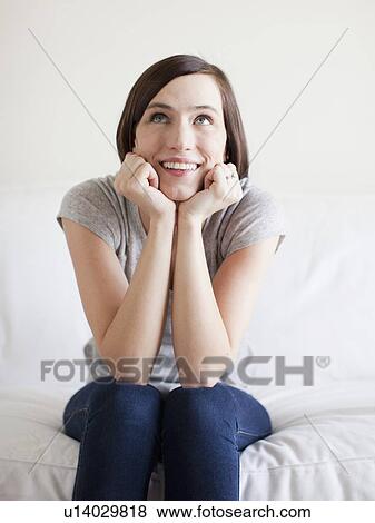Happy young woman sitting on bed View Large Photo Image Stock Photo - Happy young woman sitting on bed. Fotosearch
