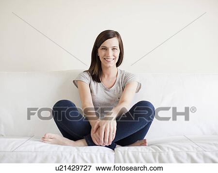Happy young woman sitting on bed View Large Photo Image Stock Photo - Happy young woman sitting on bed. Fotosearch