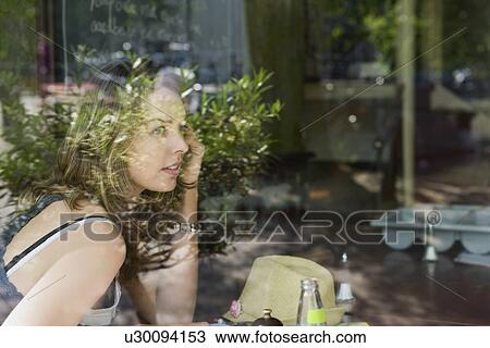 Stock Image - Holland, Amsterdam, Woman in cafe talking mobile phone. Fotosearch