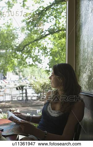 Stock Photo - Holland, Amsterdam, Woman sitting with book in cafe window. Fotosearch