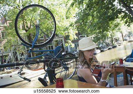 Holland, Amsterdam, Woman with guidebook sitting by canalside View Large Photo Image Stock Photography - Holland, Amsterdam, Woman with guidebook sitting by canalside. Fotosearch