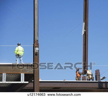 Stock Image - Male workers on construction site. Fotosearch