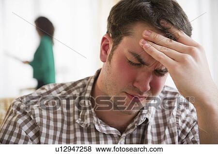 Man with head in hand, woman in background View Large Photo Image Stock Photo - Man with head in hand, woman in background. Fotosearch