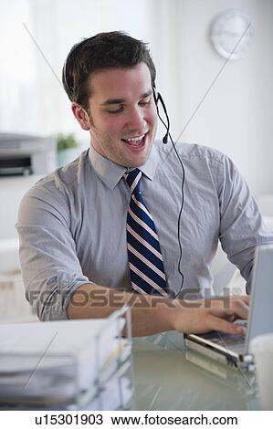 Man with headset working on laptop View Large Photo Image Stock Image - Man with headset working on laptop. Fotosearch