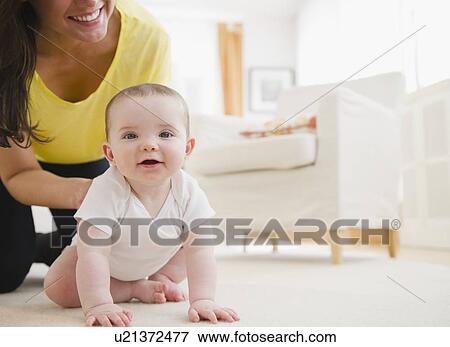 Mother and baby daughter (6-11 months) crawling on carpet View Large Photo Image Stock Photo - Mother and baby daughter (6-11 months) crawling on carpet. Fotosearch