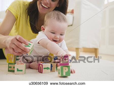 Mother and baby daughter (6-11 months) playing with blocks View Large Photo Image Stock Photo - Mother and baby daughter (6-11 months) playing with blocks. Fotosearch