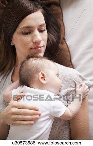 Stock Photograph - Mother and baby girl (2-5 months) sleeping together. Fotosearch