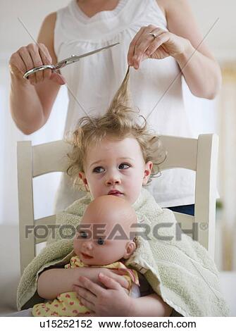 Stock Image - Mother cutting daughter's (2-3) hair. Fotosearch