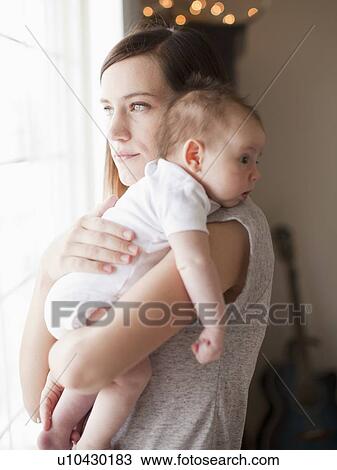 Stock Image - Mother embracing baby girl (2-5 months). Fotosearch